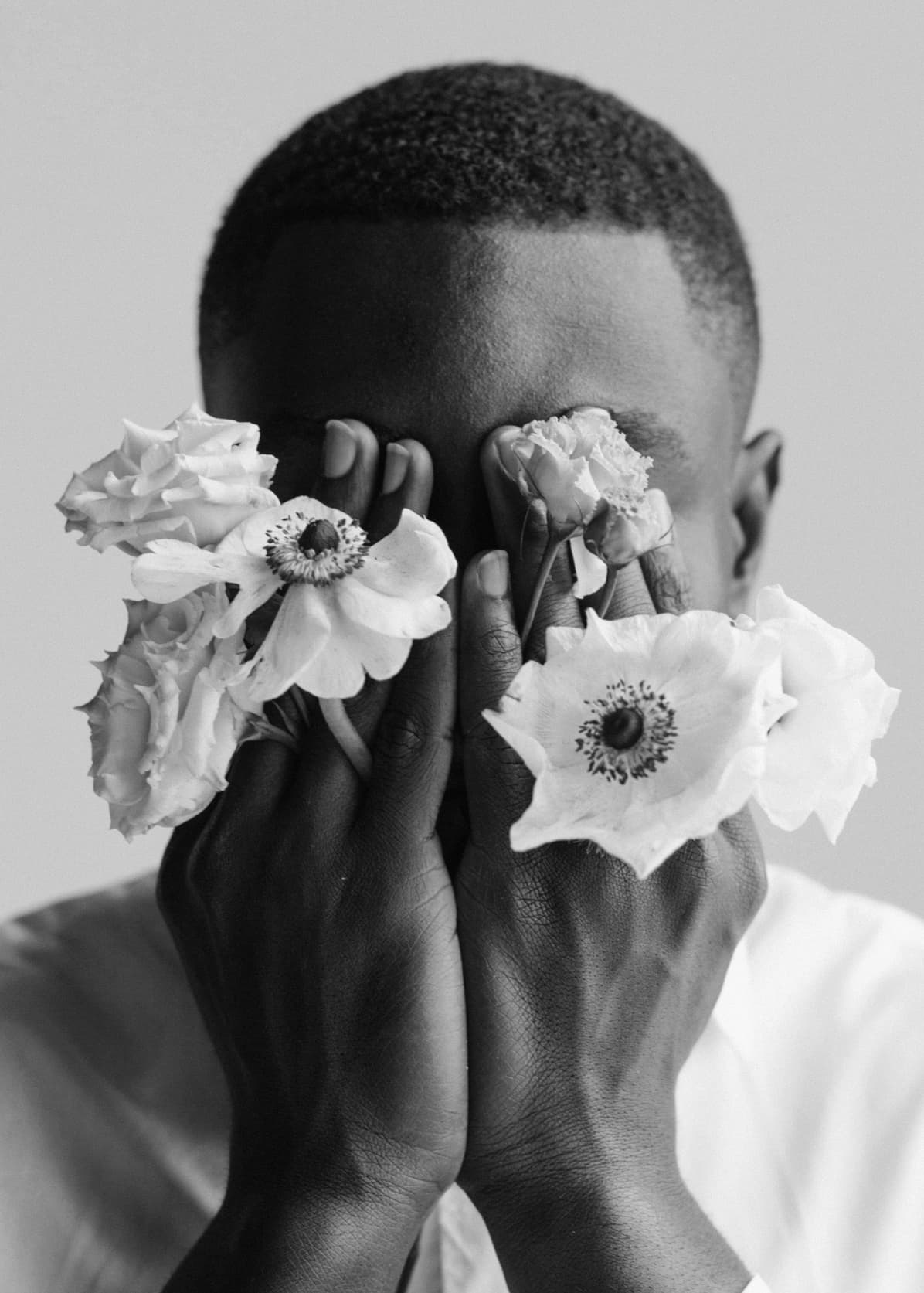 Close Up portrait of a man holding flowers against his face.